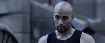 Movie still from “Resident Evil: Afterlife” (2010), directed by Paul W.S. Anderson – A man with a bald head is looking at the camera; Close Up shot, Over the shoulder angle