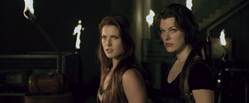 Movie still from “Resident Evil: Afterlife” (2010), directed by Paul W.S. Anderson – A couple of women standing next to each other in a room; Close Up shot, Over the shoulder angle