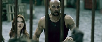 Movie still from “Resident Evil: Afterlife” (2010), directed by Paul W.S. Anderson – A bald man is standing in front of a fence; Close Up shot, Overhead angle