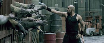 Movie still from “Resident Evil: Afterlife” (2010), directed by Paul W.S. Anderson – A man holding a gun in front of a bunch of zombies; Medium shot, Over the shoulder angle