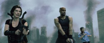 Movie still from “Resident Evil: Afterlife” (2010), directed by Paul W.S. Anderson – A man holding a gun while standing in front of a city; Medium shot, Low angle