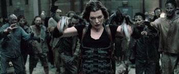 Movie still from “Resident Evil: Afterlife” (2010), directed by Paul W.S. Anderson – A woman in black shirt walking in a crowd of zombies; Medium shot, Over the shoulder angle