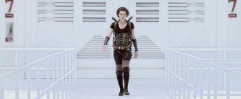 Movie still from “Resident Evil: Afterlife” (2010), directed by Paul W.S. Anderson – A woman in black shirt and boots walking down a ramp; Medium shot, Low angle