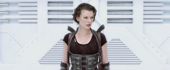 Movie still from “Resident Evil: Afterlife” (2010), directed by Paul W.S. Anderson – A woman in a black shirt and a leather vest; Medium shot, Low angle