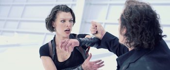 Movie still from “Resident Evil: Afterlife” (2010), directed by Paul W.S. Anderson – A woman in a black shirt and a man in a black suit are fighting; Close Up shot, Over the shoulder angle