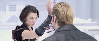 Movie still from “Resident Evil: Afterlife” (2010), directed by Paul W.S. Anderson – A woman holding a knife up to a man's face; Close Up shot, Over the shoulder angle