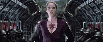 Movie still from “Resident Evil: Afterlife” (2010), directed by Paul W.S. Anderson – A woman in a purple outfit with a spider necklace; Medium shot, Over the shoulder angle