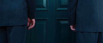 Movie still from “Resident Evil: Apocalypse” (2004), directed by Alexander Witt – Two people are standing in front of a green door; Medium shot, Overhead angle