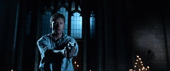 Movie still from “Resident Evil: Apocalypse” (2004), directed by Alexander Witt – A man holding a gun while standing in a dark room; Medium shot, Low angle