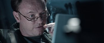 Movie still from “Resident Evil: Apocalypse” (2004), directed by Alexander Witt – A man smoking a cigarette while looking at a computer screen; Close Up shot, Over the shoulder angle