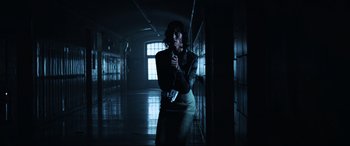 Movie still from “Resident Evil: Apocalypse” (2004), directed by Alexander Witt – A woman standing in a dark room holding a remote; Wide shot, Low angle