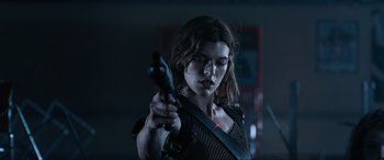 Movie still from “Resident Evil: Apocalypse” (2004), directed by Alexander Witt – A woman is holding a gun in a dark room; Close Up shot, Low angle