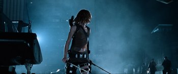 Movie still from “Resident Evil: Apocalypse” (2004), directed by Alexander Witt – A woman with a bow and arrow in a dark room; Medium shot, Low angle
