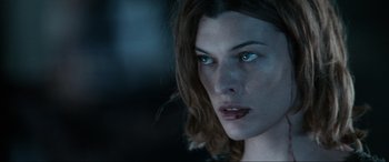 Movie still from “Resident Evil: Apocalypse” (2004), directed by Alexander Witt – A woman's face in a dimly - lit room; Close Up shot, Over the shoulder angle