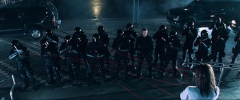 Movie still from “Resident Evil: Apocalypse” (2004), directed by Alexander Witt – A group of men in black suits standing next to each other on a street; Wide shot, High angle