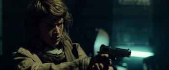 Movie still from “Resident Evil: Extinction” (2007), directed by Russell Mulcahy – A person holding a gun in a dark room; Close Up shot, Over the shoulder angle