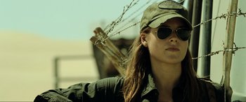 Movie still from “Resident Evil: Extinction” (2007), directed by Russell Mulcahy – A woman wearing a hat and sunglasses holding a stick; Close Up shot, Low angle