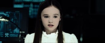 Movie still from “Resident Evil: Extinction” (2007), directed by Russell Mulcahy – A young girl with long black hair wearing a white dress; Close Up shot, Low angle