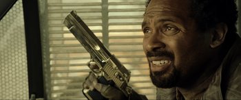 Movie still from “Resident Evil: Extinction” (2007), directed by Russell Mulcahy – A person holding a gun in a room; Close Up shot, Over the shoulder angle