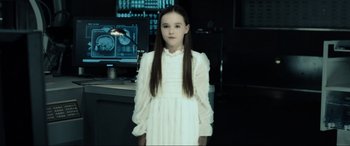 Movie still from “Resident Evil: Extinction” (2007), directed by Russell Mulcahy – A girl in a white dress standing in front of computer screens; Medium shot, Over the shoulder angle