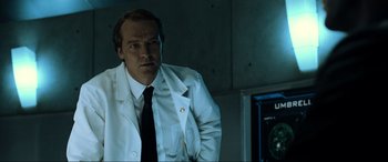 Movie still from “Resident Evil: Extinction” (2007), directed by Russell Mulcahy – A man in a white lab coat standing in front of a monitor; Medium shot, Low angle