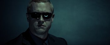 Movie still from “Resident Evil: Extinction” (2007), directed by Russell Mulcahy – A person wearing a suit and sunglasses; Close Up shot, Low angle