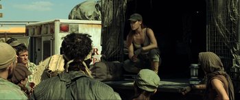 Movie still from “Resident Evil: Extinction” (2007), directed by Russell Mulcahy – A group of people standing around in front of a truck; Medium shot, Over the shoulder angle