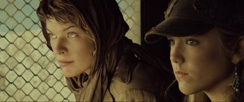 Movie still from “Resident Evil: Extinction” (2007), directed by Russell Mulcahy – A woman wearing a brown jacket and a man wearing a brown hat; Close Up shot, Low angle