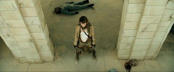 Movie still from “Resident Evil: Extinction” (2007), directed by Russell Mulcahy – A woman standing in front of a dead body; Wide shot, Overhead angle