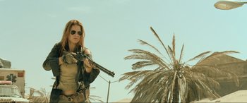 Movie still from “Resident Evil: Extinction” (2007), directed by Russell Mulcahy – A woman holding a gun while standing next to a palm tree; Medium shot, Low angle