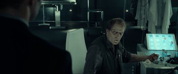 Movie still from “Resident Evil: Extinction” (2007), directed by Russell Mulcahy – A man sitting in a chair in a dark room; Medium shot, Over the shoulder angle