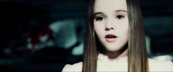 Movie still from “Resident Evil: Extinction” (2007), directed by Russell Mulcahy – A little girl with long brown hair looking at the camera; Close Up shot, Low angle
