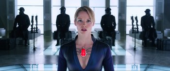 Movie still from “Resident Evil: Retribution” (2012), directed by Paul W.S. Anderson – A woman wearing a spider necklace standing in front of two statues; Close Up shot, Low angle