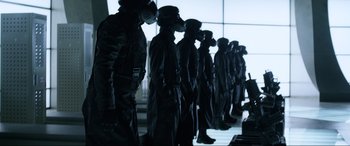 Movie still from “Resident Evil: Retribution” (2012), directed by Paul W.S. Anderson – A group of men in black suits standing next to each other in a room; Medium shot, Low angle