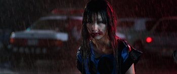 Movie still from “Resident Evil: Retribution” (2012), directed by Paul W.S. Anderson – A woman with blood on her face and mouth in the rain; Close Up shot, Over the shoulder angle