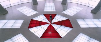 Movie still from “Resident Evil: Retribution” (2012), directed by Paul W.S. Anderson – A person standing in a room with a umbrella floor; Extreme Wide shot, Overhead angle