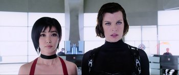 Movie still from “Resident Evil: Retribution” (2012), directed by Paul W.S. Anderson – A woman in a black top standing next to another woman in a red top; Close Up shot, Low angle