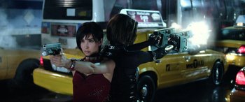 Movie still from “Resident Evil: Retribution” (2012), directed by Paul W.S. Anderson – A woman holding a gun in front of another woman in front of a yellow taxi cab; Close Up shot, Over the shoulder angle