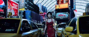 Movie still from “Resident Evil: Retribution” (2012), directed by Paul W.S. Anderson – A woman in a red dress walking through a busy street; Wide shot, Low angle