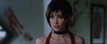 Movie still from “Resident Evil: Retribution” (2012), directed by Paul W.S. Anderson – A woman in a red top with a black choker; Close Up shot, Over the shoulder angle
