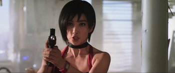 Movie still from “Resident Evil: Retribution” (2012), directed by Paul W.S. Anderson – A woman holding a gun while wearing a red shirt; Close Up shot, Low angle