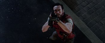 Movie still from “Resident Evil: Retribution” (2012), directed by Paul W.S. Anderson – A man in a red vest is holding a gun; Medium shot, Overhead angle