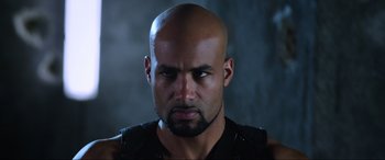 Movie still from “Resident Evil: Retribution” (2012), directed by Paul W.S. Anderson – A bald man with a beard is staring at the camera; Close Up shot, Low angle