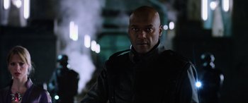 Movie still from “Resident Evil: Retribution” (2012), directed by Paul W.S. Anderson – A man in a black jacket is looking at the camera; Close Up shot, Over the shoulder angle