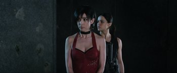 Movie still from “Resident Evil: Retribution” (2012), directed by Paul W.S. Anderson – A woman in a red dress standing next to another woman in a red dress; Close Up shot, Over the shoulder angle