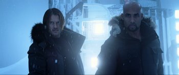 Movie still from “Resident Evil: Retribution” (2012), directed by Paul W.S. Anderson – Two men standing next to each other in the snow; Medium shot, Low angle