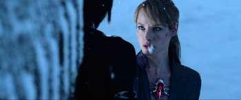 Movie still from “Resident Evil: Retribution” (2012), directed by Paul W.S. Anderson – A woman with a knife in her mouth looking out a window; Close Up shot, Over the shoulder angle