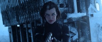 Movie still from “Resident Evil: Retribution” (2012), directed by Paul W.S. Anderson – A woman holding a gun while standing next to a wall; Close Up shot, Low angle