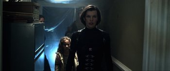 Movie still from “Resident Evil: Retribution” (2012), directed by Paul W.S. Anderson – A woman and a child in a hallway with lights on; Medium shot, Low angle