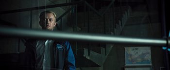 Movie still from “Resident Evil: The Final Chapter” (2016), directed by Paul W.S. Anderson – A man standing in front of stairs in a building; Medium shot, Low angle